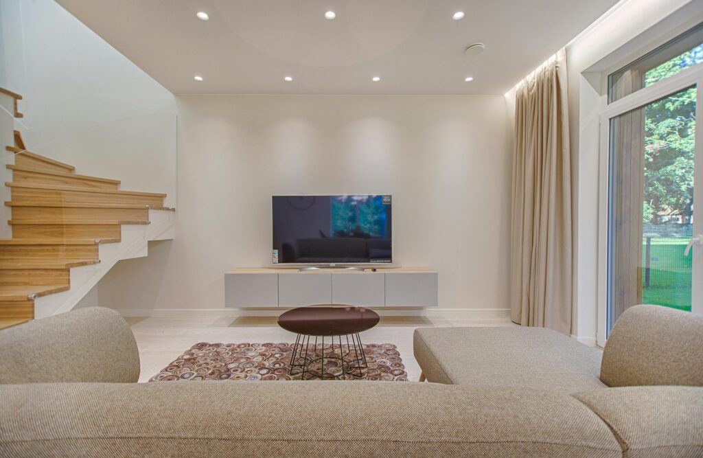 Contemporary living room with stylish sofa, TV, and staircase, offering a cozy interior design setting.