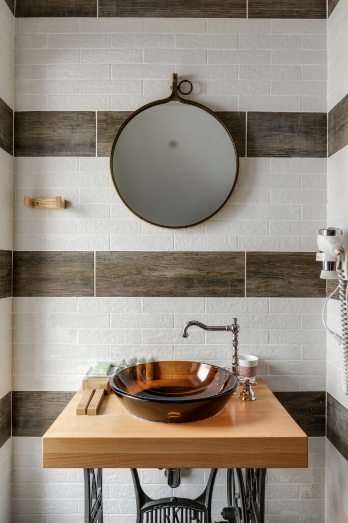 Stylish bathroom interior featuring a modern vessel sink, round mirror, and unique design elements.